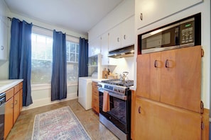 A kitchen with a stove, oven, microwave, and wooden cabinets.
