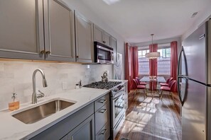 A modern kitchen with stainless steel appliances, a large island with seating, and a view to the dining area.