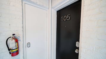 A white door with a black door number '105' and a fire extinguisher mounted on the wall beside it.