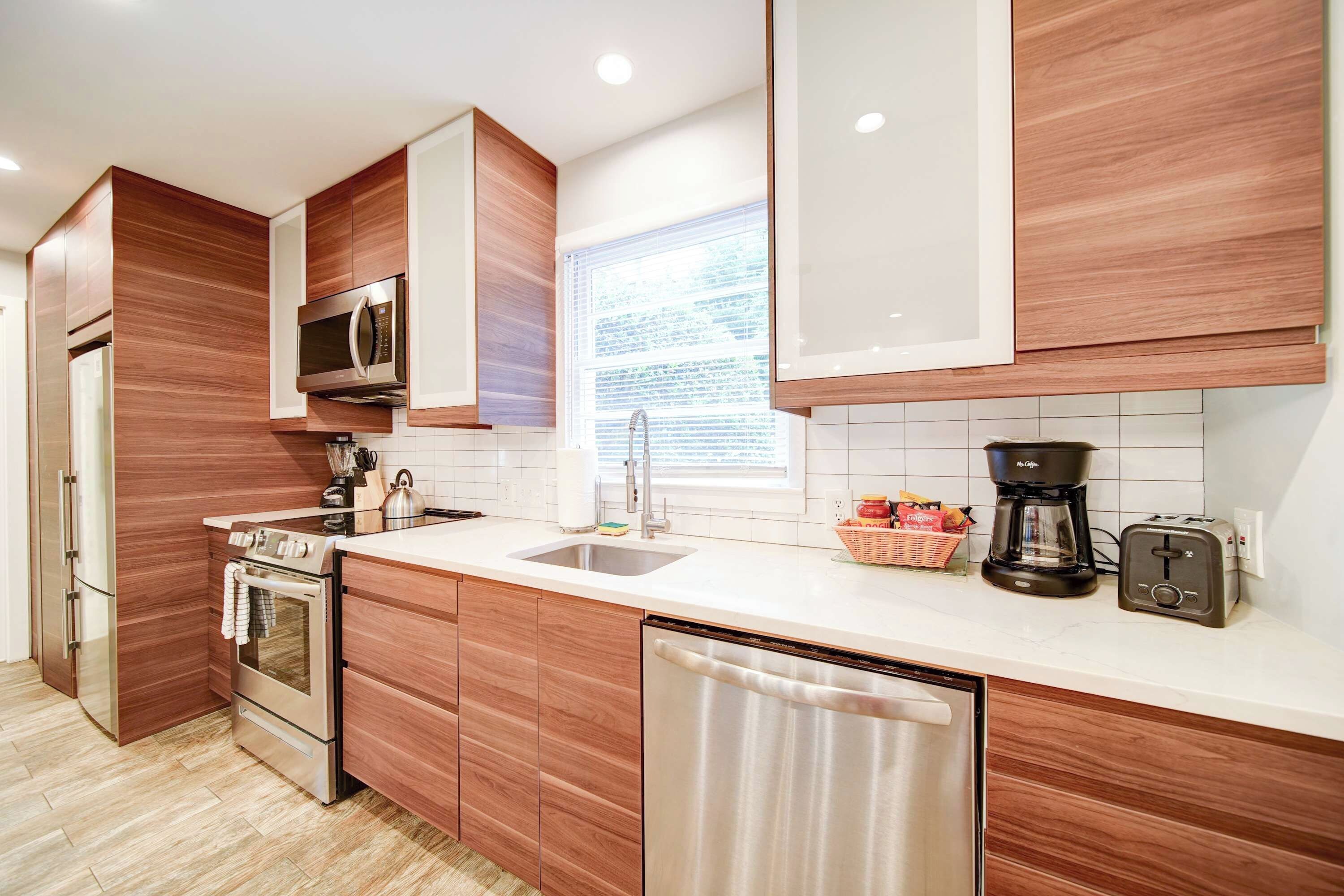 Een moderne keuken met houten kasten, roestvrijstalen apparatuur, een vaatwasser en een koffiezetapparaat.