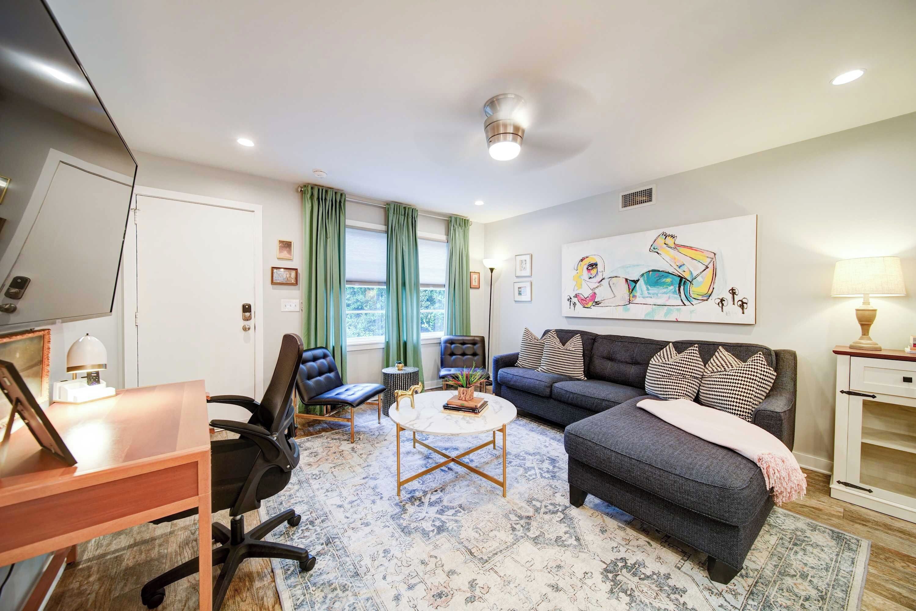 A modern living room with a sofa, chairs, a coffee table, and artwork on the wall.
