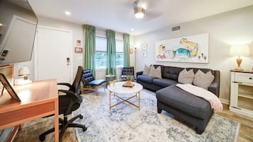 A modern living room with a sofa, chairs, a coffee table, and artwork on the wall.