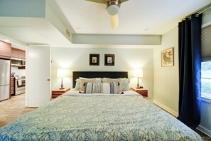 A bedroom with a bed, two bedside tables, a ceiling fan, and a window with curtains.