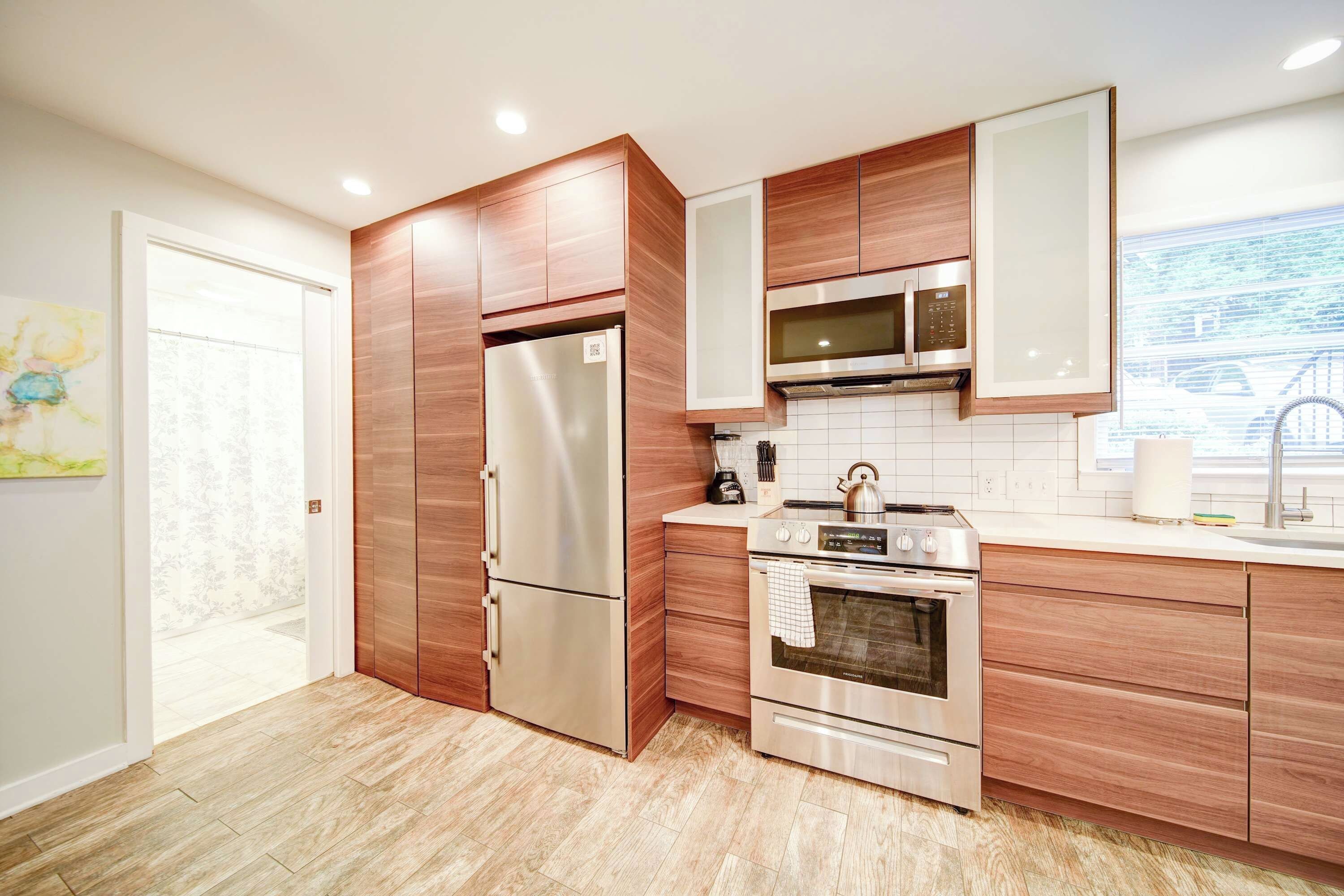 A modern kitchen with stainless steel appliances, wooden cabinetry, and a tiled backsplash.