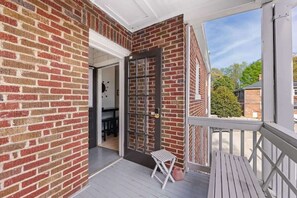 A brick exterior with a door leading to a covered porch.