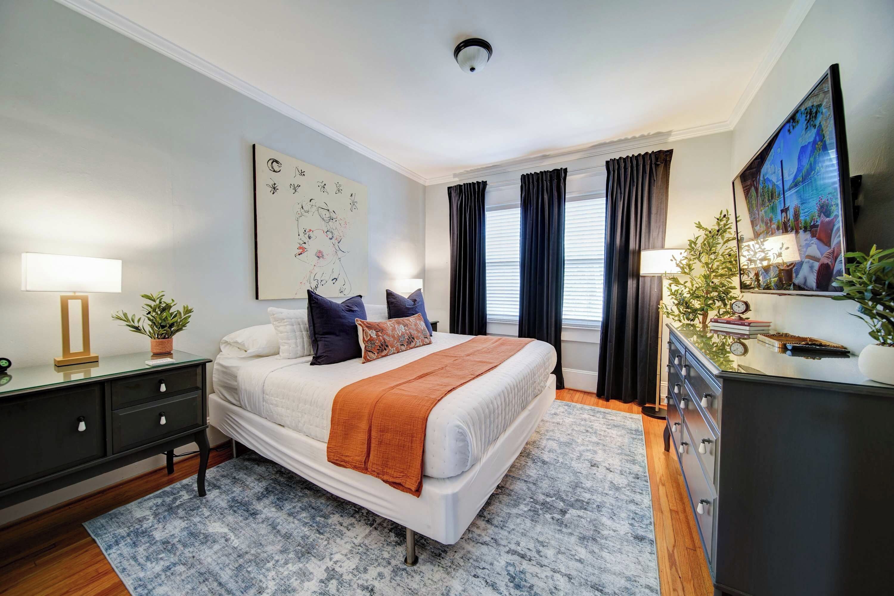 Unwind in a beautifully furnished Charlotte boutique hotel bedroom featuring a comfortable bed, stylish décor, hardwood floors, and natural light.