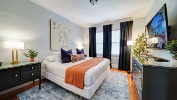 Unwind in a beautifully furnished Charlotte boutique hotel bedroom featuring a comfortable bed, stylish décor, hardwood floors, and natural light.