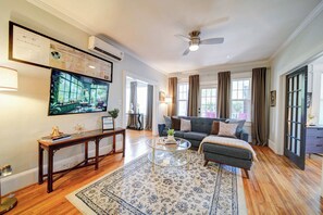 A living room with a sofa, coffee table, and a large flat-screen TV mounted on the wall. - Boutique 2BR Dilworth Condo | Near Atrium and Novant Health (Charlotte)
