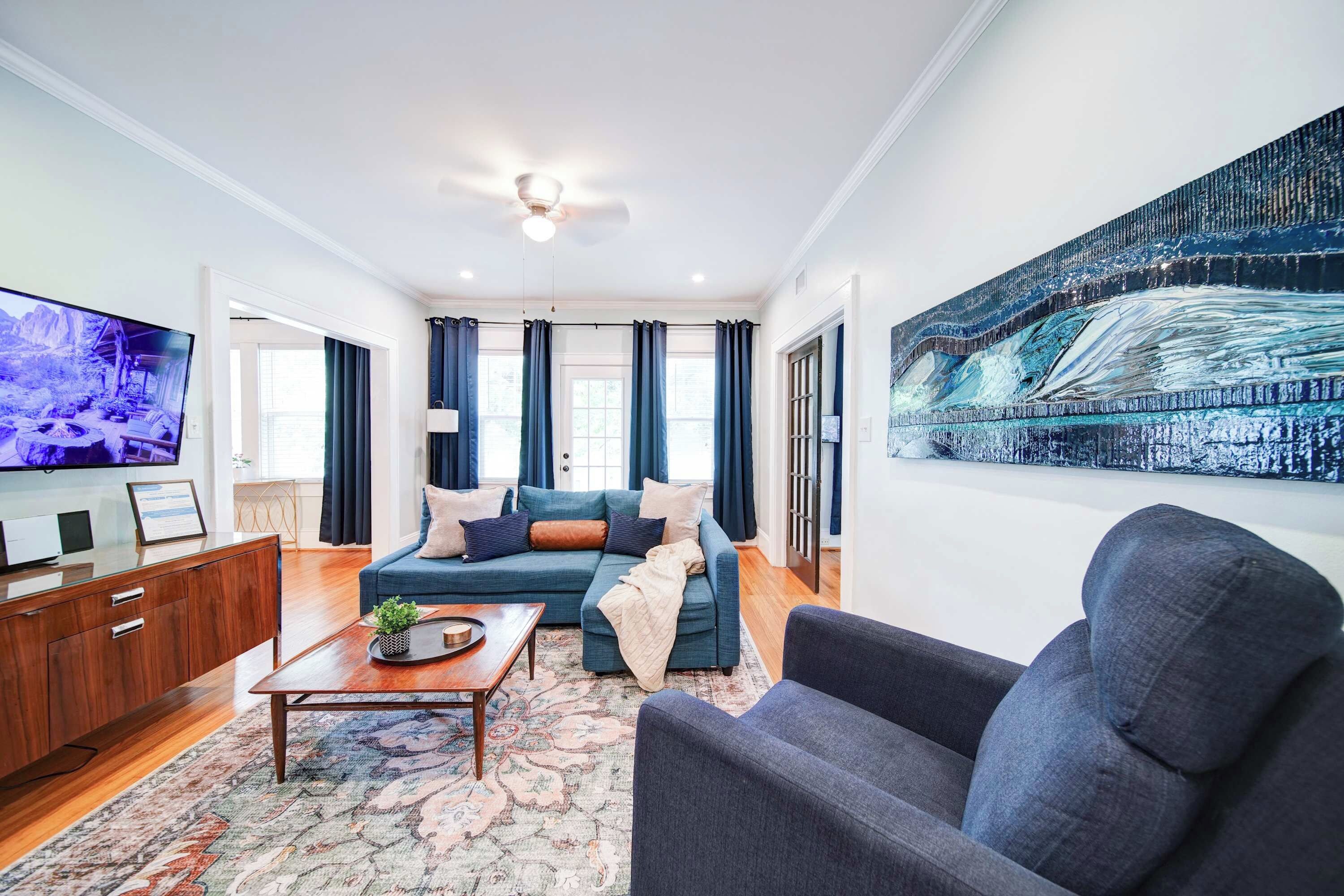 Relax in a stylish Charlotte boutique hotel suite featuring a spacious living area, comfortable seating, Smart TV, and beautiful hardwood floors.