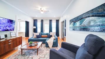 Relax in a stylish Charlotte boutique hotel suite featuring a spacious living area, comfortable seating, Smart TV, and beautiful hardwood floors.