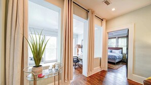 Un couloir avec une table en verre, une plante en pot et un lit dans la pièce adjacente.
