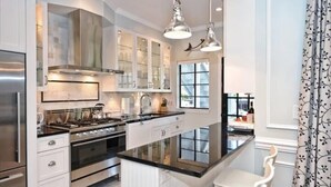 A modern kitchen with a central island, stainless steel appliances, and pendant lighting.