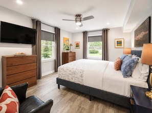 A bedroom with a bed, a dresser, a TV, and a ceiling fan. - Modern Myers Park 1BR · Ground Floor · Free Parking near Atrium CMC & Uptown (Charlotte)