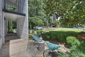 A modern building with a balcony, a paved outdoor area with chairs, and a well-maintained lawn. - Modern Myers Park 1BR · Ground Floor · Free Parking near Atrium CMC & Uptown (Charlotte)