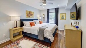 A bedroom with a bed, bedside tables, a dresser, a ceiling fan, and artwork on the walls.