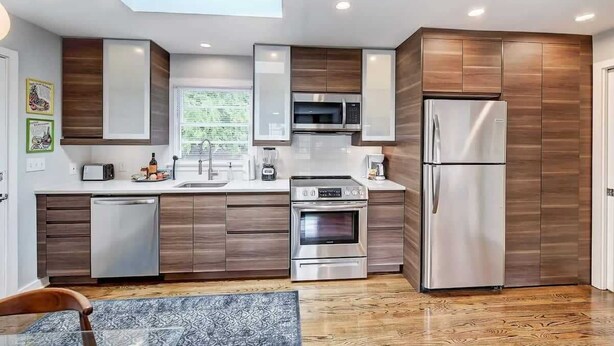A modern kitchen with built-in appliances, a dishwasher, and a dining area with a patterned rug.