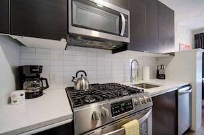 A kitchen with a stainless steel stove, a microwave, a coffee maker, and a dishwasher.