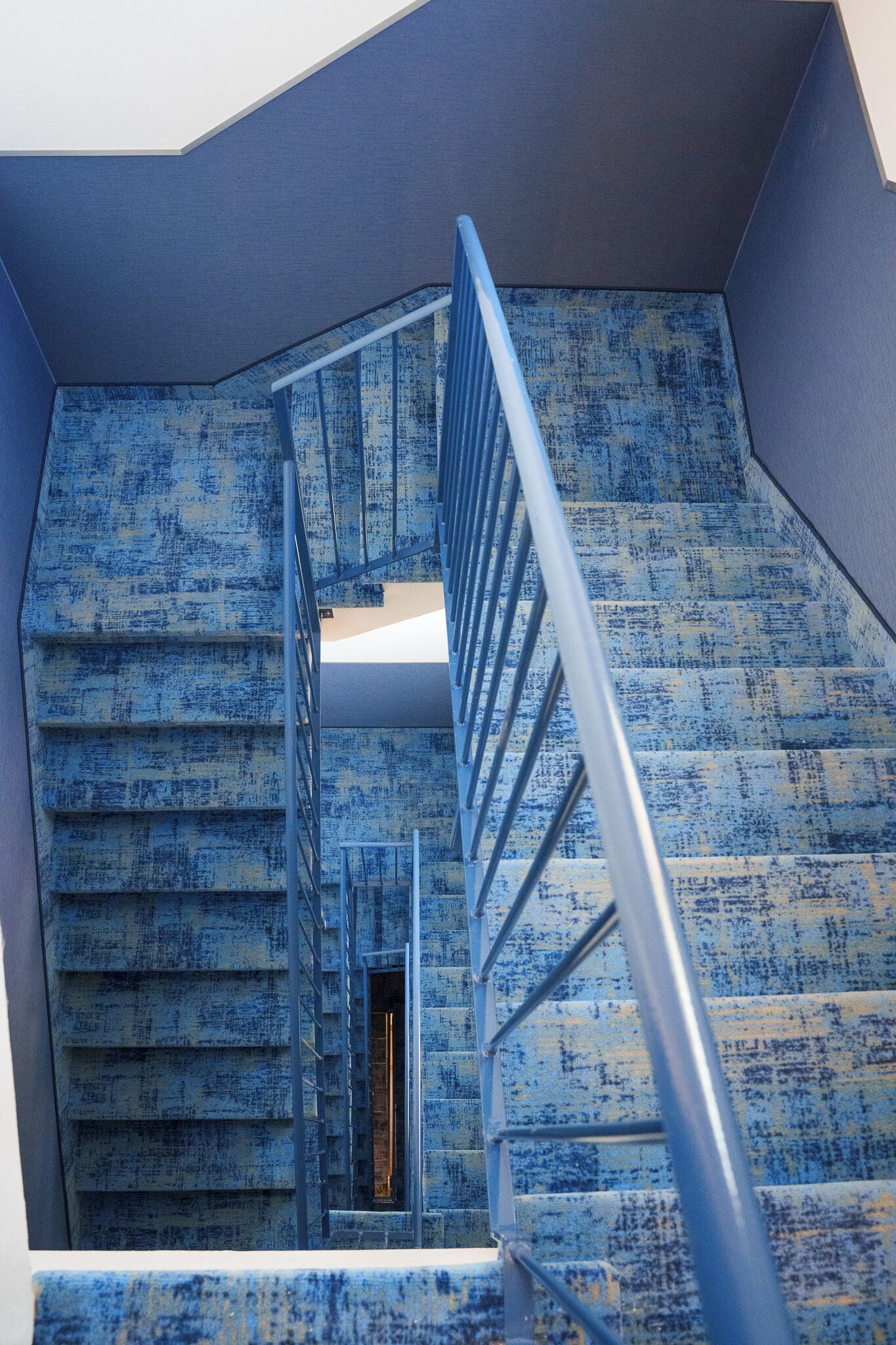 Un escalier avec une rampe métallique menant à un palier.
