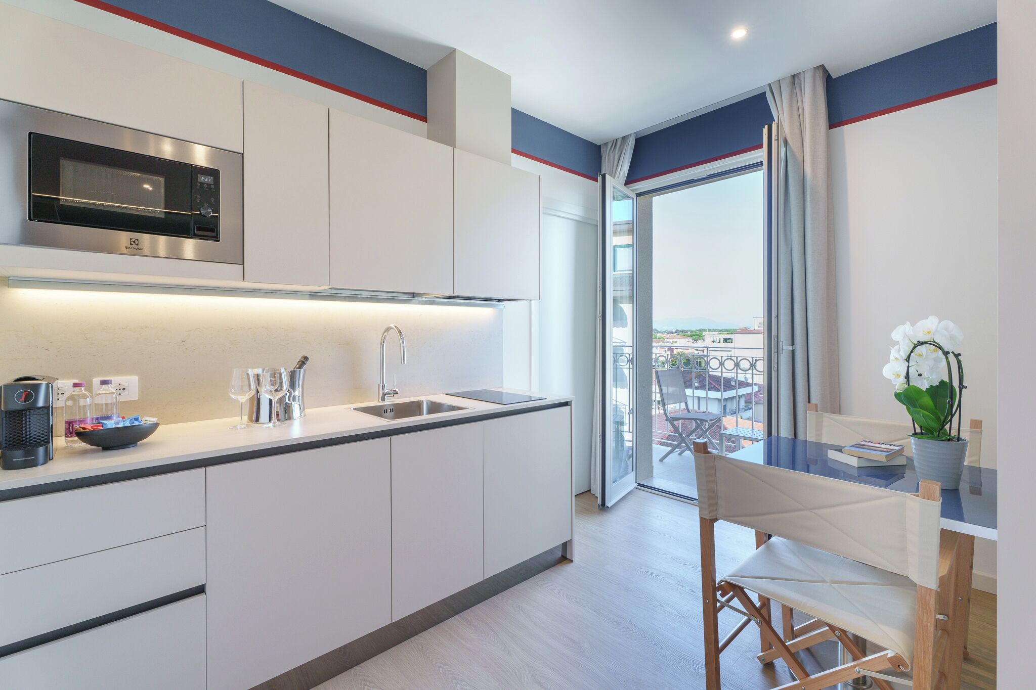 Una cocina moderna con microondas integrado, un fregadero y un comedor con mesa y sillas.