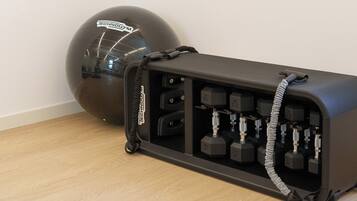 A gym with a black exercise ball and a weight bench with adjustable weights.