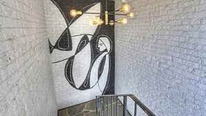 Un escalier agrémenté d’un luminaire moderne et d’une fresque murale.