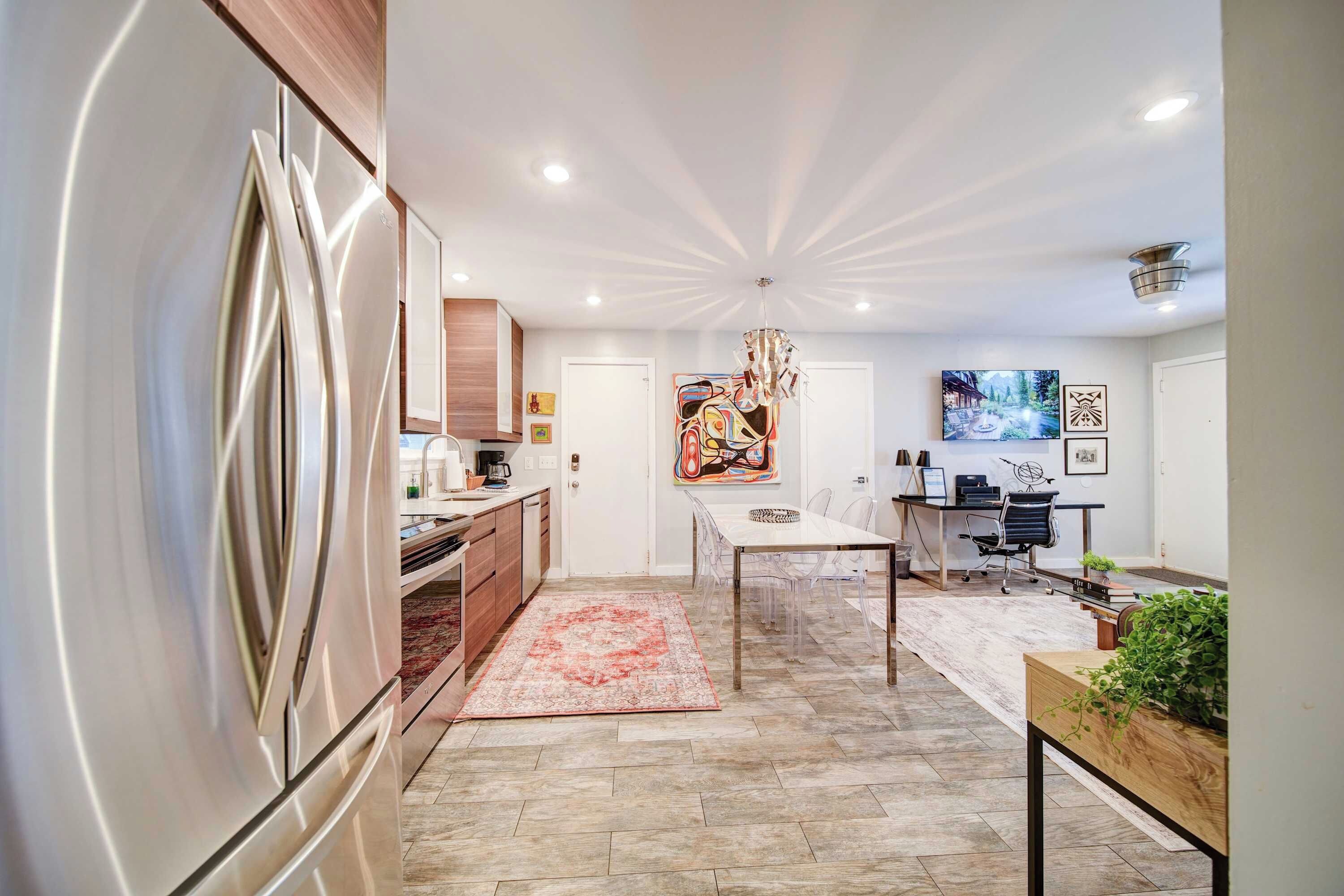 A modern kitchen with a built-in refrigerator, wooden cabinets, and a dining area with a table and chairs.