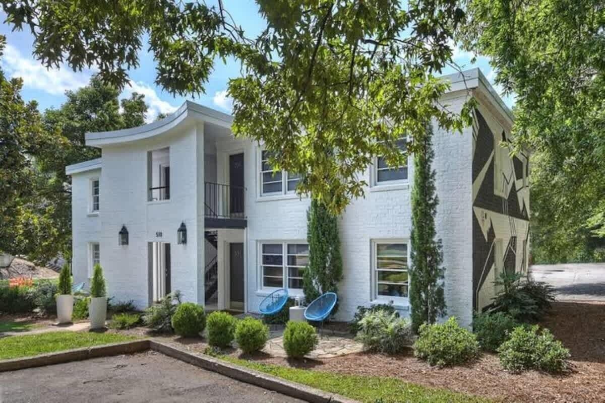 A modern two-story house with a curved facade, satellite dishes, and a well-maintained garden.