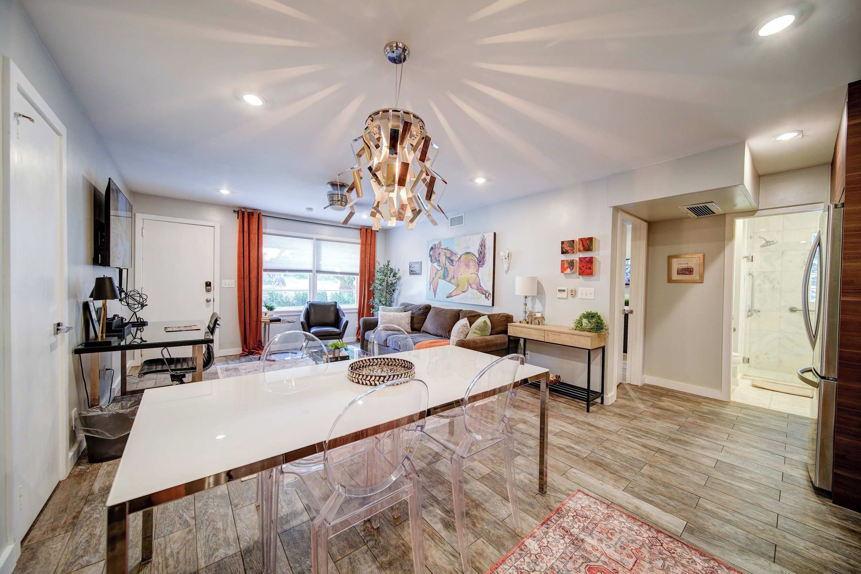 Una cucina moderna con isola centrale, sedie trasparenti e lampadario.