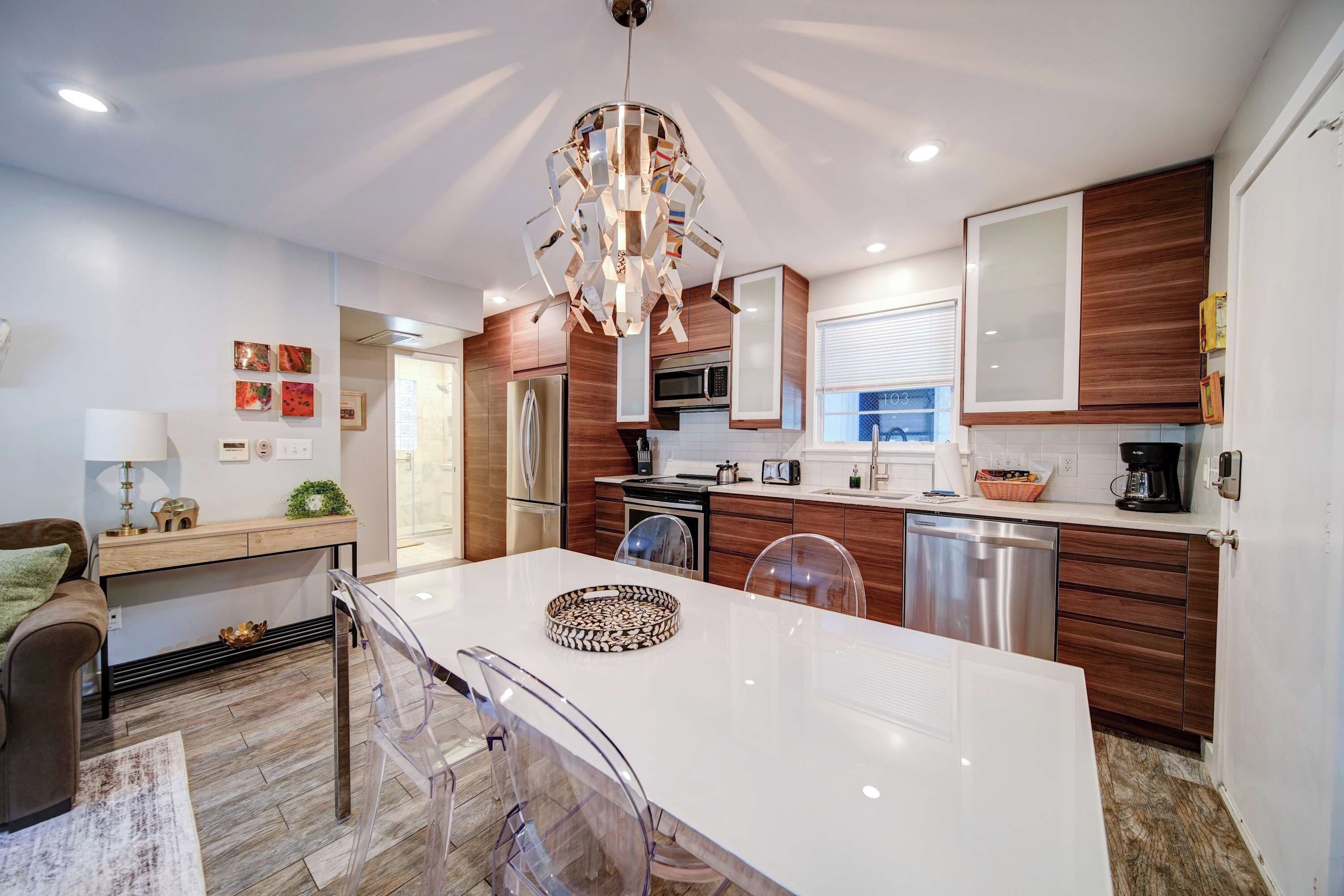 Een moderne keuken met een centraal eiland, houten kastjes, roestvrijstalen apparatuur en een bijzondere kroonluchter.