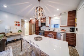 Een moderne keuken met een centraal eiland, houten kastjes, roestvrijstalen apparatuur en een bijzondere kroonluchter.