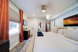 Ein modernes Schlafzimmer mit einem großen Bett, einem Schreibtisch und einem Fenster mit Vorhängen.