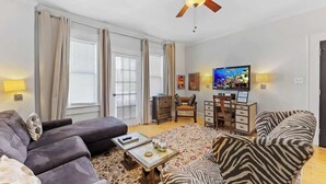 Un salon comprenant un canapé, un fauteuil, une table basse et un téléviseur.
