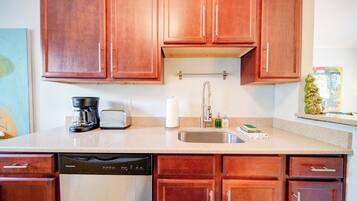 A kitchen with wooden cabinets, a coffee maker, a toaster, a dish soap dispenser, and a dish rack.