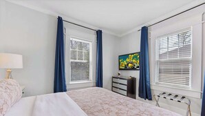 A bedroom with a bed, a dresser, a radiator, and a painting on the wall.