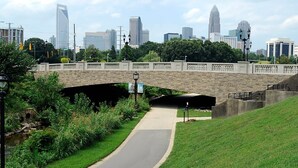 Un pont de pierre enjambe un chemin pavé, avec une vue sur les bâtiments d’une ville en arrière-plan.