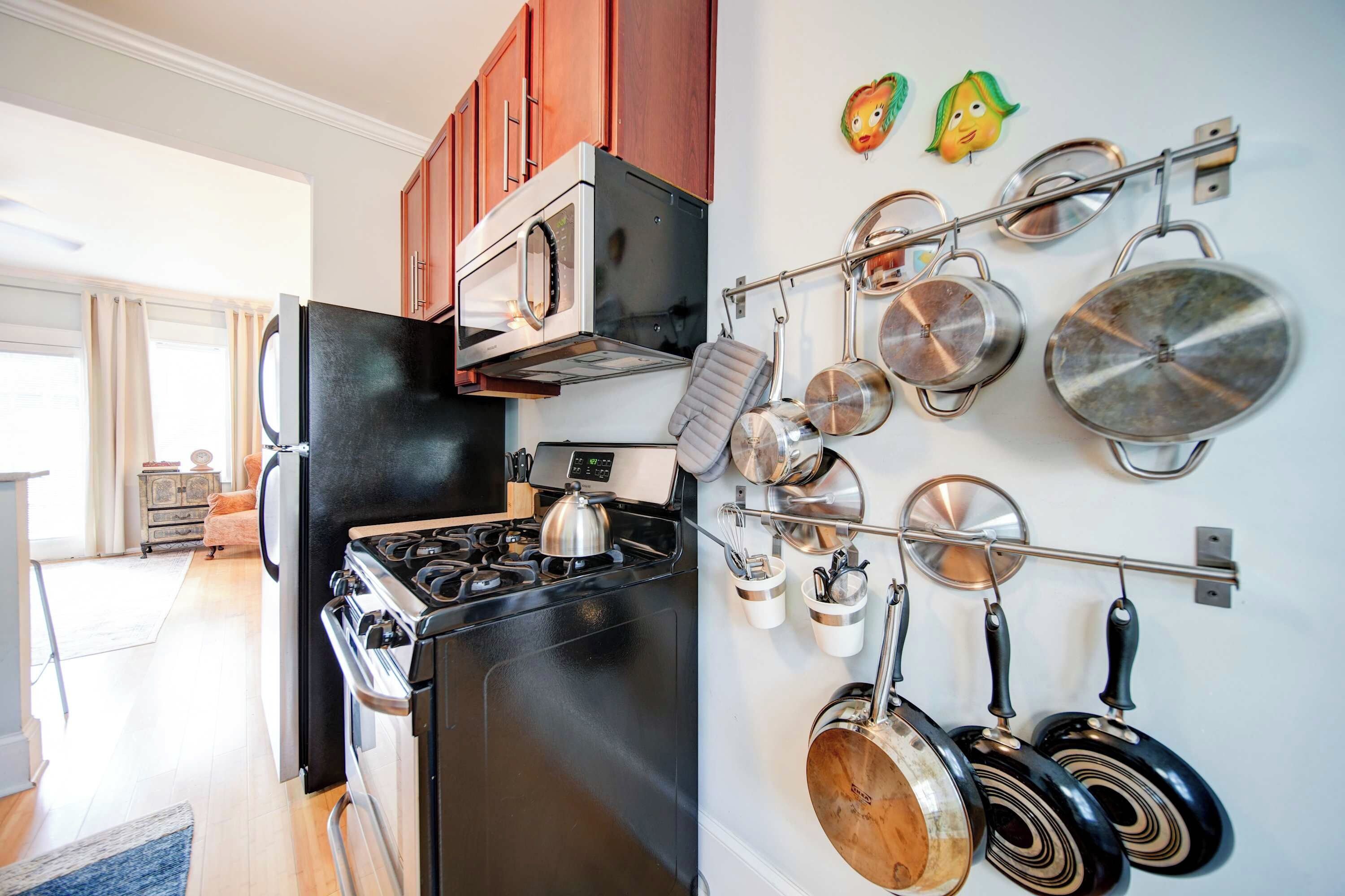 A kitchen with a stove, oven, and pots hanging on the wall.