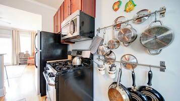 A kitchen with a stove, oven, and pots hanging on the wall.