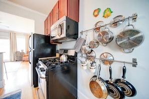A kitchen with a stove, oven, and pots hanging on the wall. - The Home Collection: King Suite with Private Balcony near Atrium & South End (Charlotte)