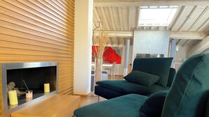 A modern living room with a wooden slatted wall, a sofa, a fireplace, and a dining area in the background. - Luxury View Terrace Apartment (Firenze)