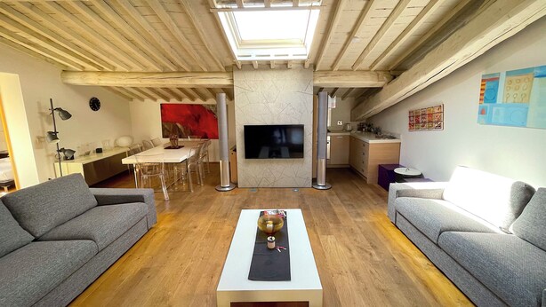 A modern living room with a large TV, grey sofas, a dining area, and a kitchen. - Luxury View Terrace Apartment (Firenze)