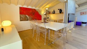 A dining area with a white table, clear chairs, and a red abstract painting on the wall. - Luxury View Terrace Apartment (Firenze)