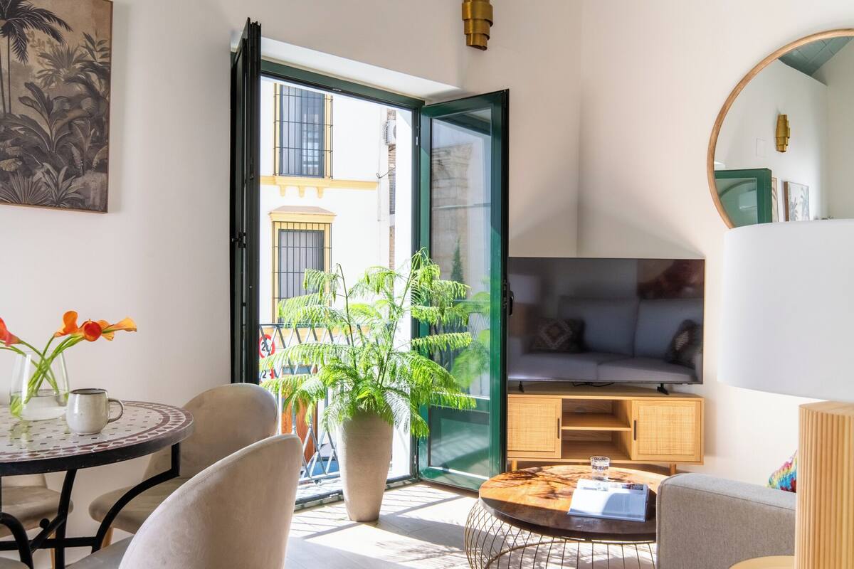 Una sala de estar moderna con una mesa redonda, un sofá, un televisor y un comedor con sillas y una mesa.