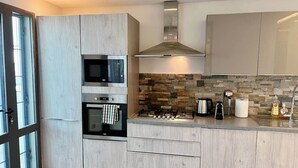 A modern kitchen with built-in appliances, a stone backsplash, and a large window. - Almadies Peaceful Oasis | 24/7 Security |Casa Molo (Dakar)
