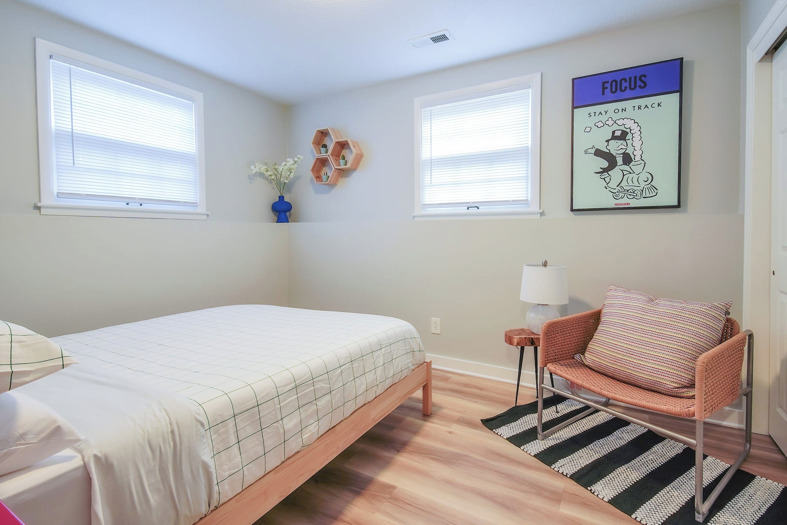 A bedroom with a bed, a chair, a rug, and a wall with a poster.