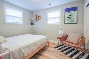 A bedroom with a bed, a chair, a rug, and a wall with a poster. - Playful, walkable, and comfortable, just steps from Mass Street. (Lawrence)