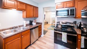 A modern kitchen with wooden cabinets, stainless steel appliances, and a granite countertop. - Playful, walkable, and comfortable, just steps from Mass Street. (Lawrence)