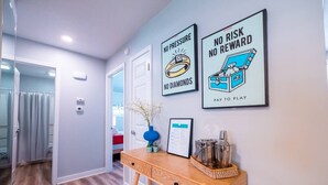 A hallway with a wooden console table, two framed motivational posters, a vase with flowers, and a framed menu on the wall. - Playful, walkable, and comfortable, just steps from Mass Street. (Lawrence)