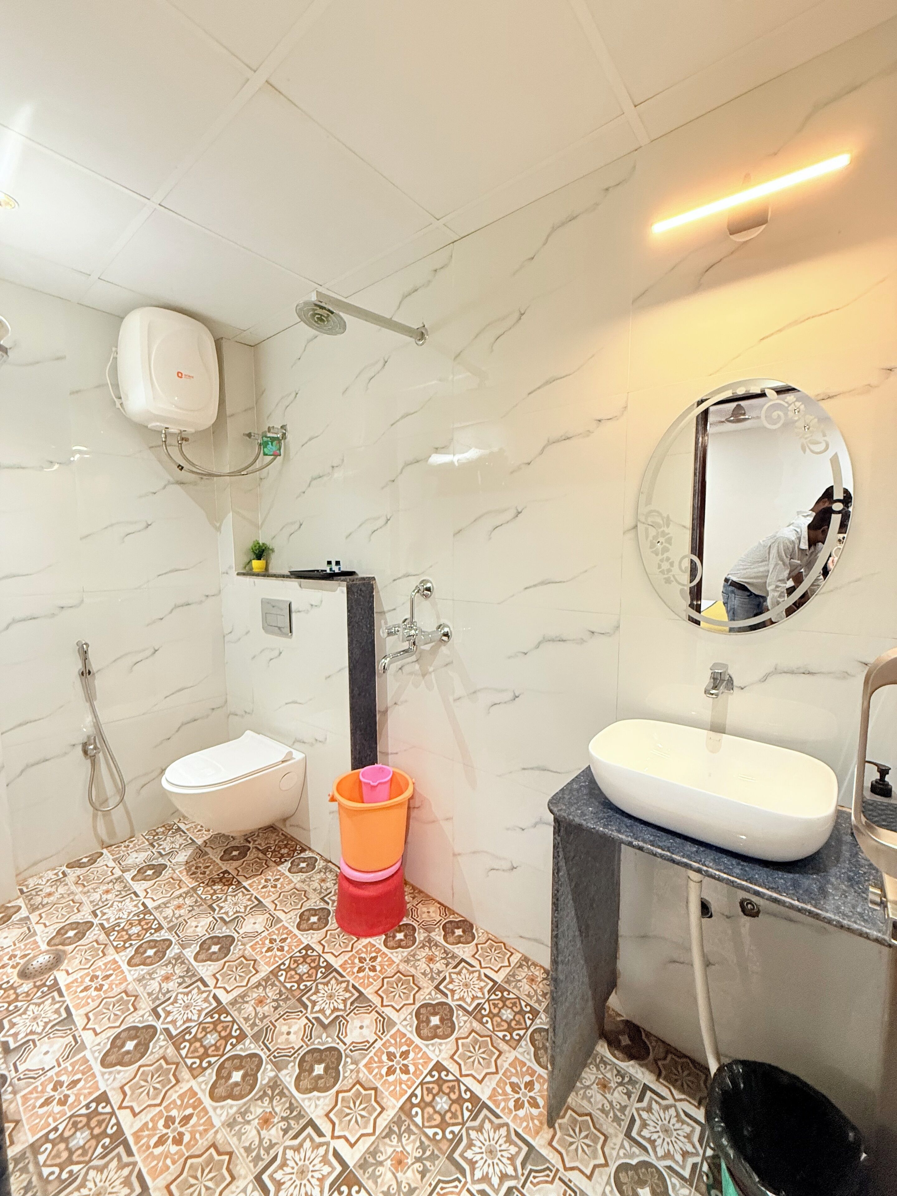 A bathroom with a toilet, sink, shower, and a mirror.