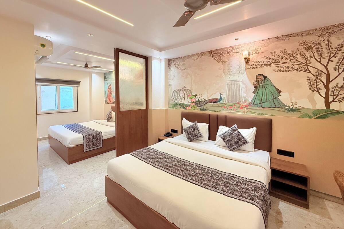 A hotel room with two beds, a ceiling fan, a mural, and a window.