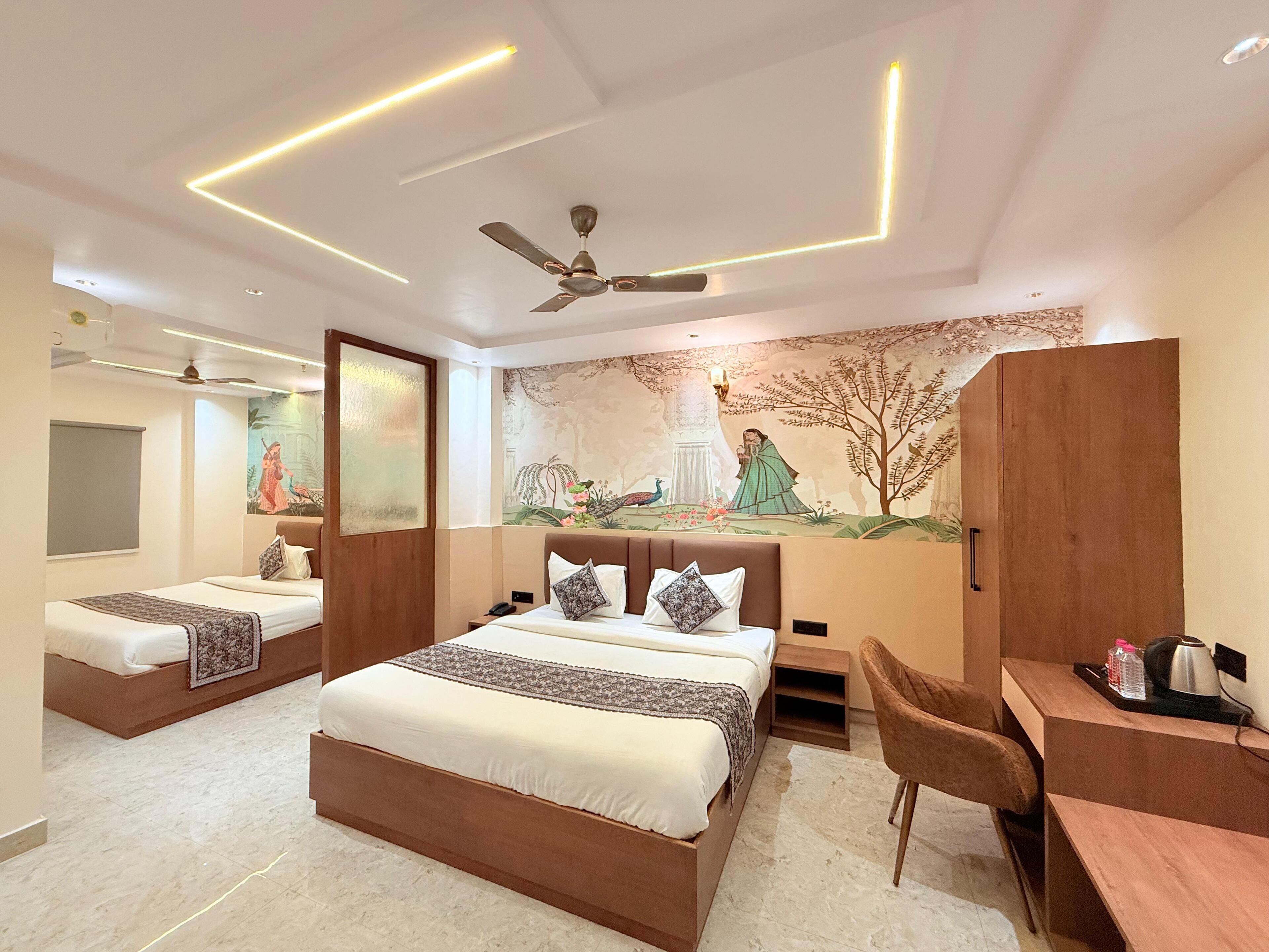 A modern hotel room with a large bed, a desk, and a ceiling fan.